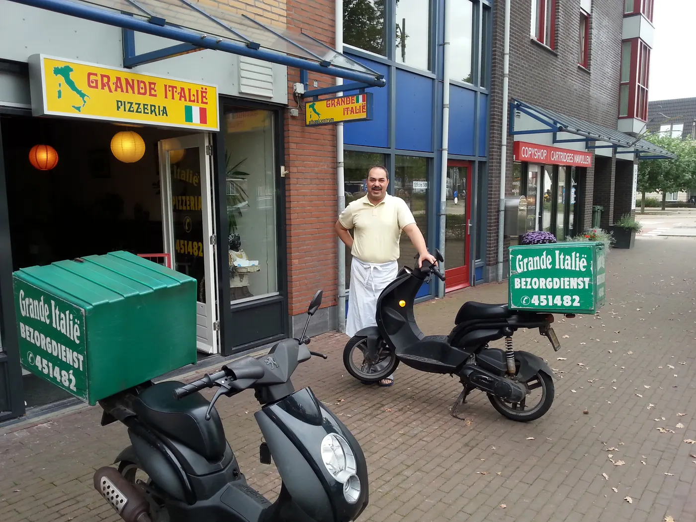 De bezorgscooter van Grande Italië met groene bezorgbox.
