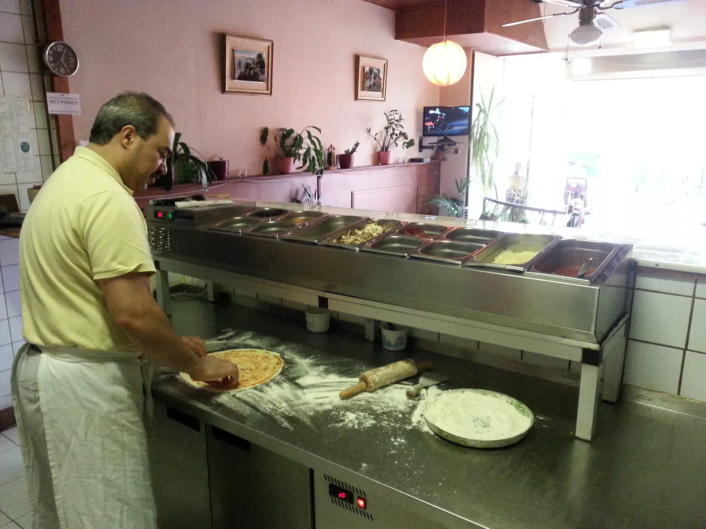 Mario bereidt een pizza met verse ingrediënten.