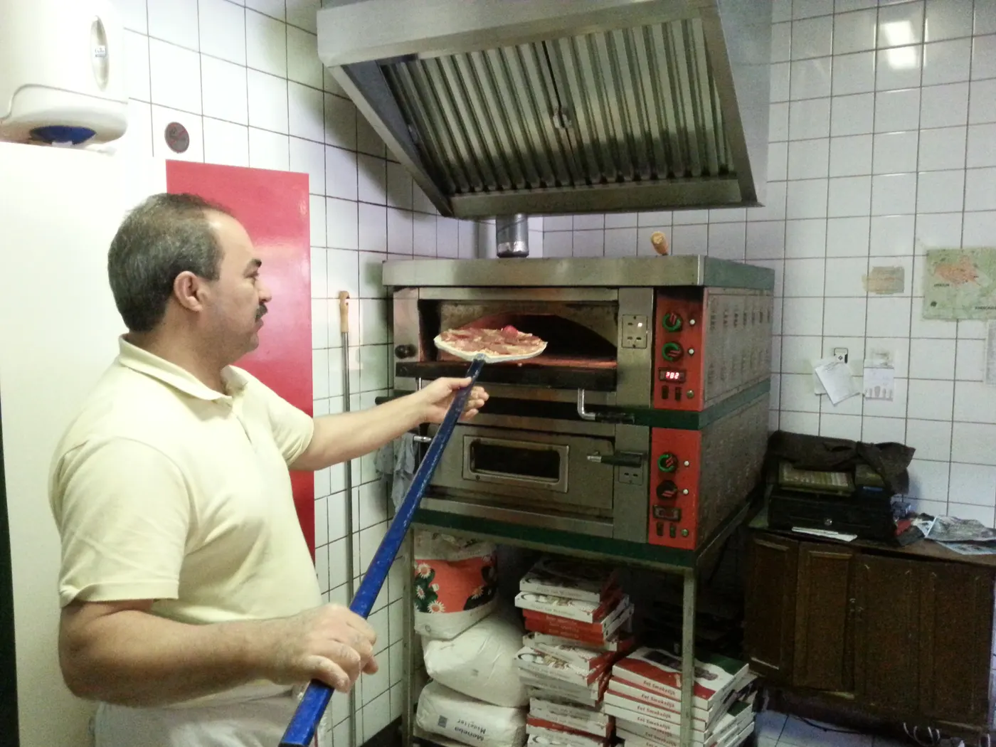 Mario schuift een pizza in de oven.